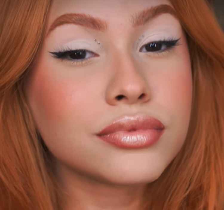 mulher ruiva de pele clara com maquiagem leve e lábios nude brilhante