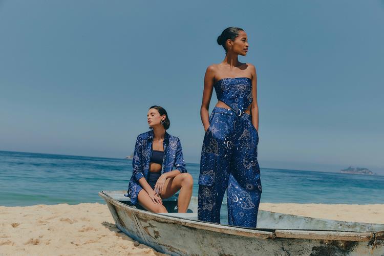 duas mulheres na praia com conjuntos azuis de estampa branca