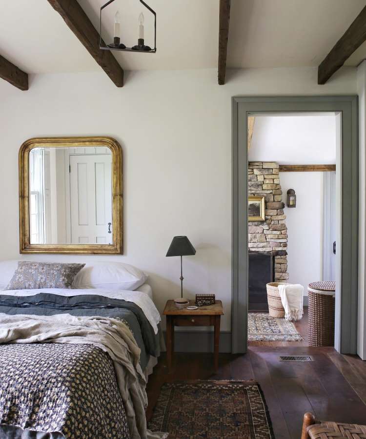 Elemento reflexivo quadrado no ambiente, pendurado na parede, em cima da cama. Cores predominantes: madeira, cinza e marrom