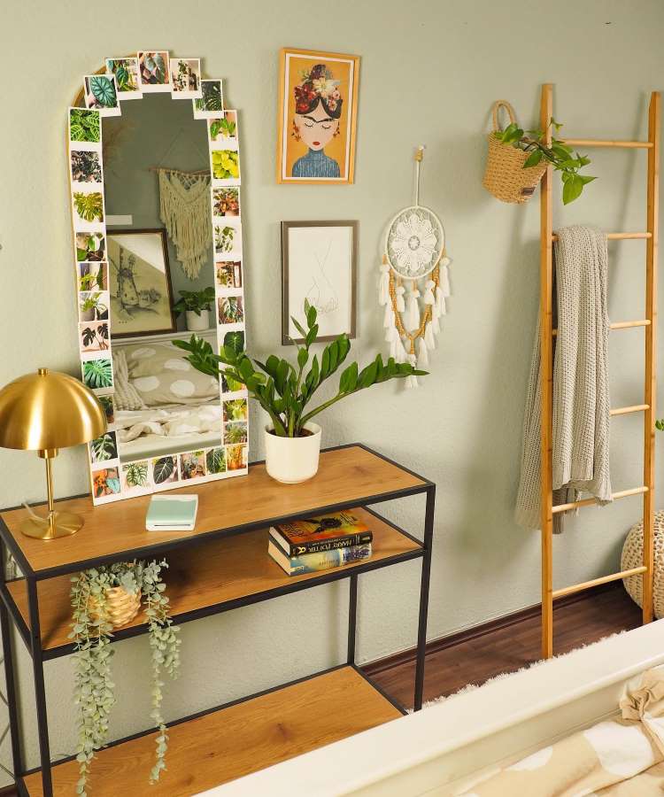 Quarto com espelho emoldurado de fotos de plantas sob móvel. Cores predominantes: madeira, verde, branco e dourado