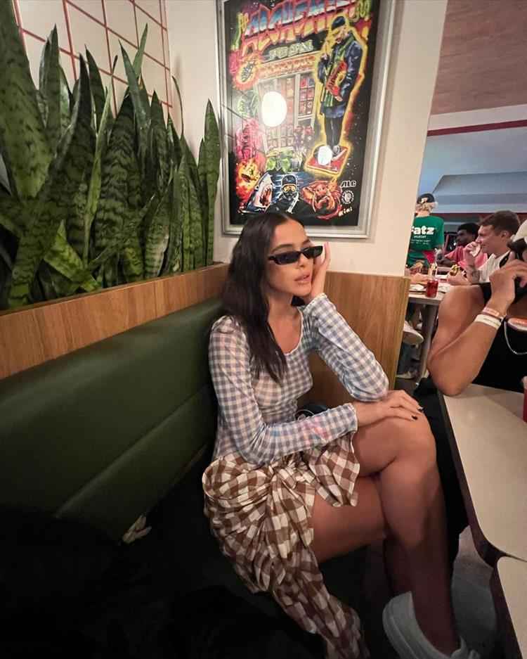 Bruna Marquezine com saia curta xadrez marrom e blusa de mesma estampa azul