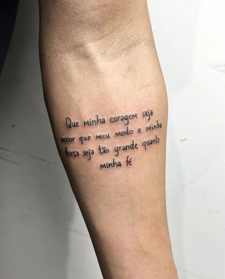 tatuagem escrita Que minha coragem seja maior que meu medo e minha força seja tão grande quanto minha fé no braço