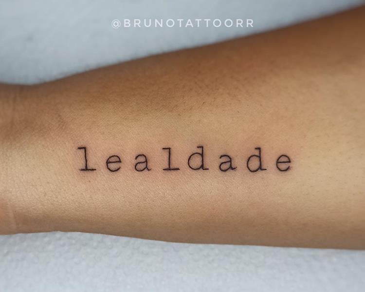 tatuagem escrita lealdade no braço