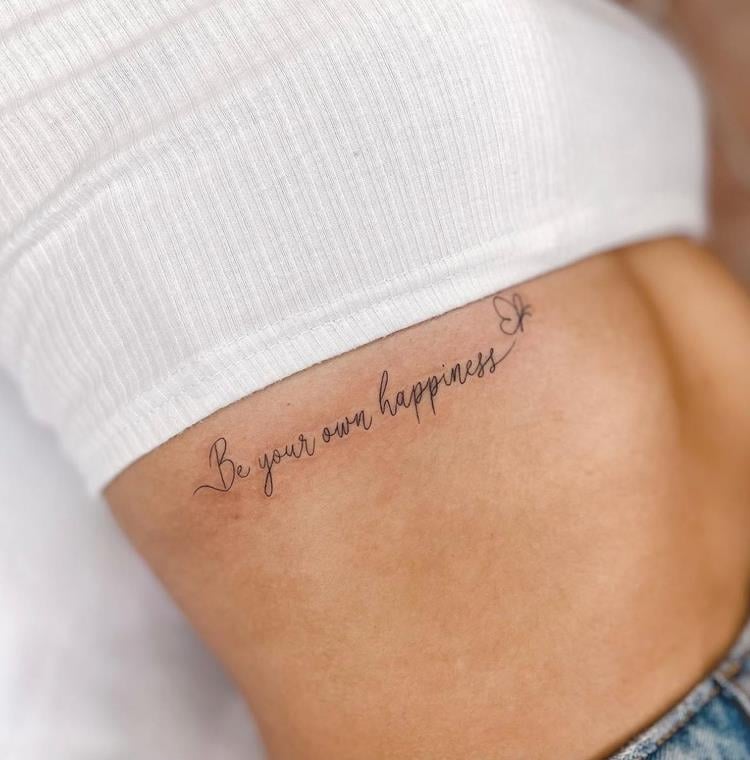tatuagem escrita Be your own happiness (seja sua própria felicidade) na costela