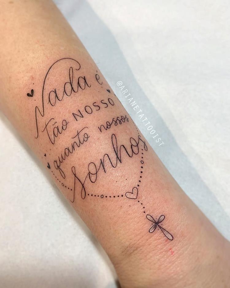 tatuagem escrita Nada é tão nosso quanto nosso sonho no braço