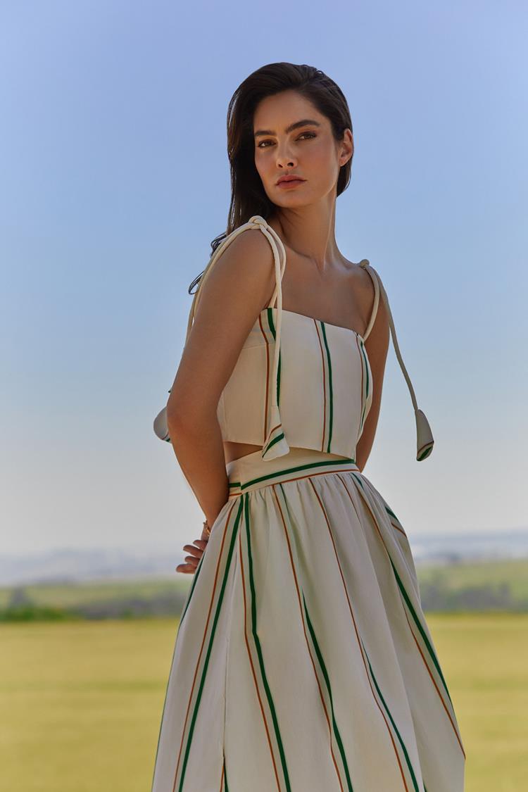mulher com conjunto branco de listas verdes, top de alça e saia longa