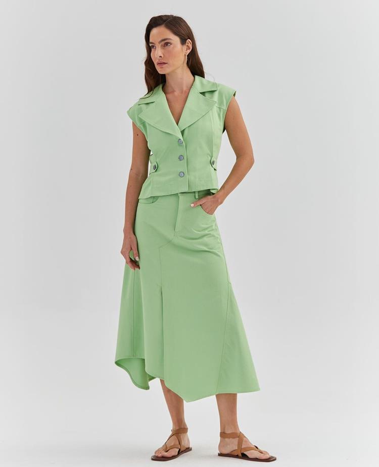 mulher com look verde claro, colete e saia midi