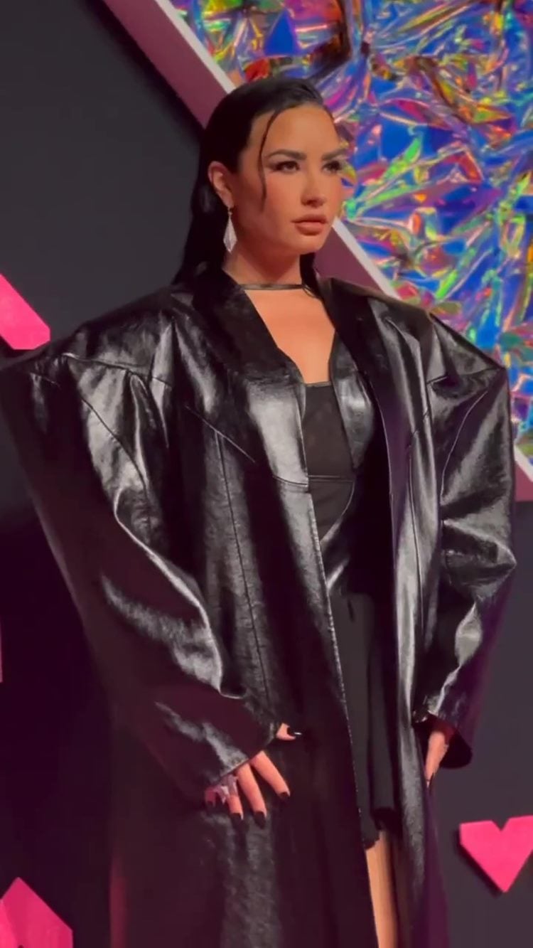 Cantora Demi Lovato no VMA 2023, com vestido preto e jaqueta longa de couro