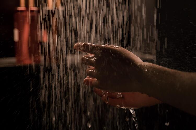 Mãos femininas na água de um chuveiro