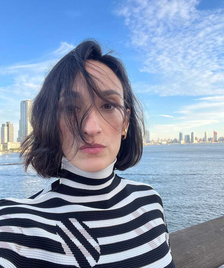 Selfie da esposa do apresentador, de frente a mar, usando blusa de listras preta e branca