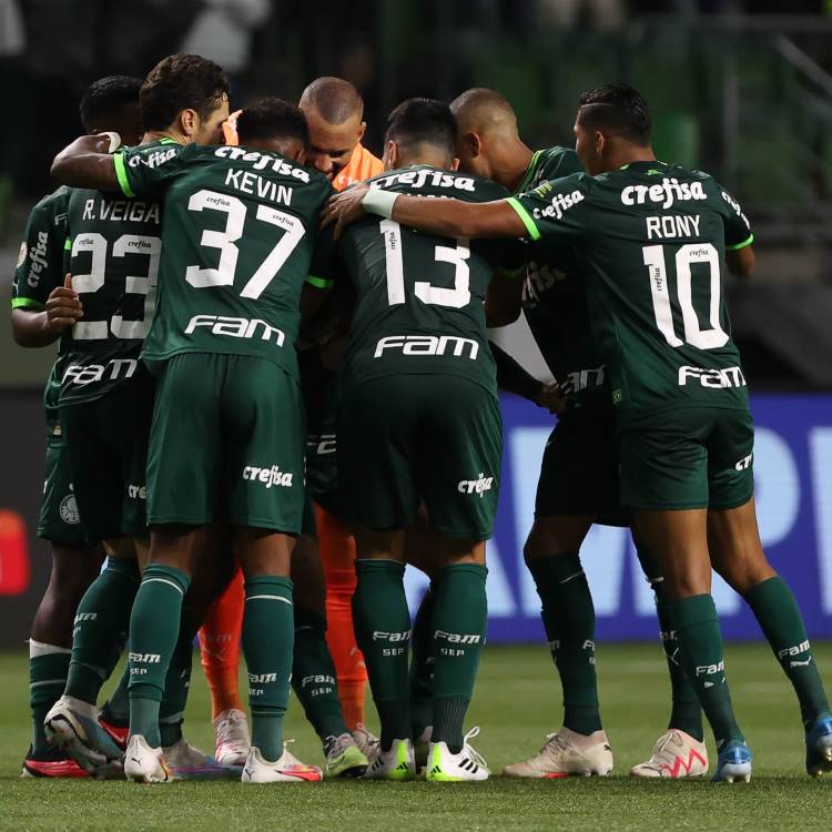 Elenco do Palmeiras usando o primeiro uniforme (verde escuro) se abraçando no gramado. 