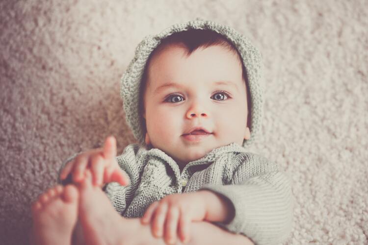bebê co cerca de um ano com olhos claros e cabelos escuros usando roupas de frio