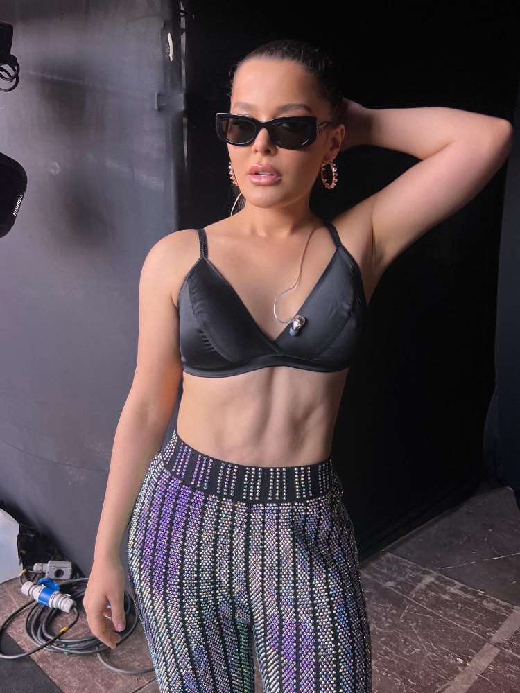 Antes e depois da Lipo HD de Maraisa, da dupla com Maiara. Hoje, foto dela usando top preto, calça brilhante, com a barriga exposta, em camarim de show