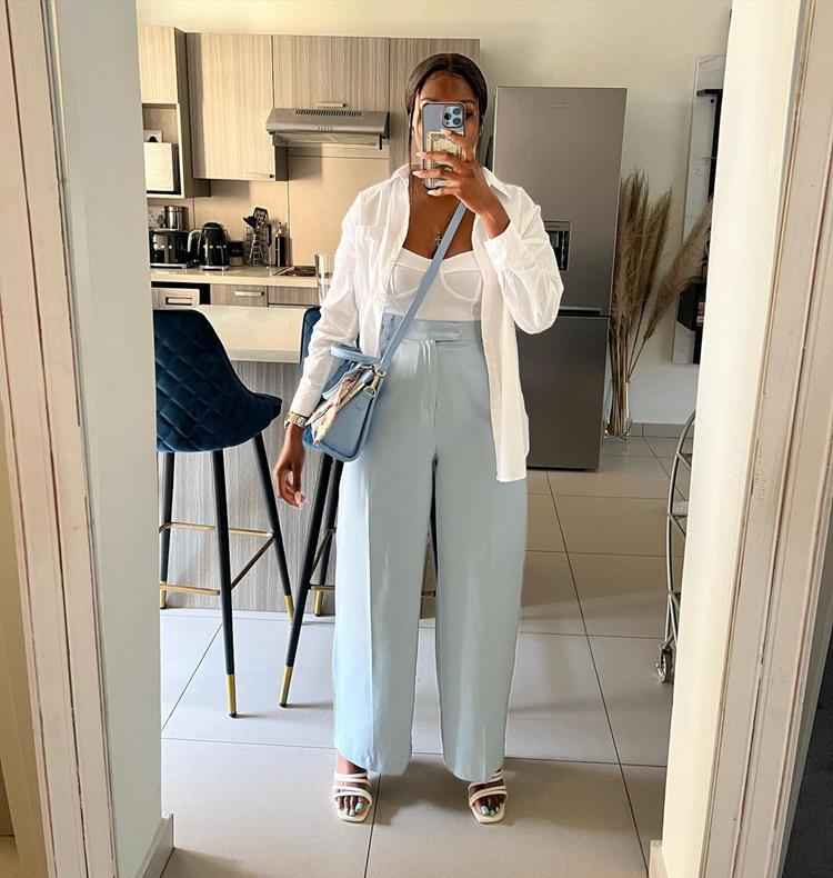 mulher com calça azul pastel, top e camisa branca