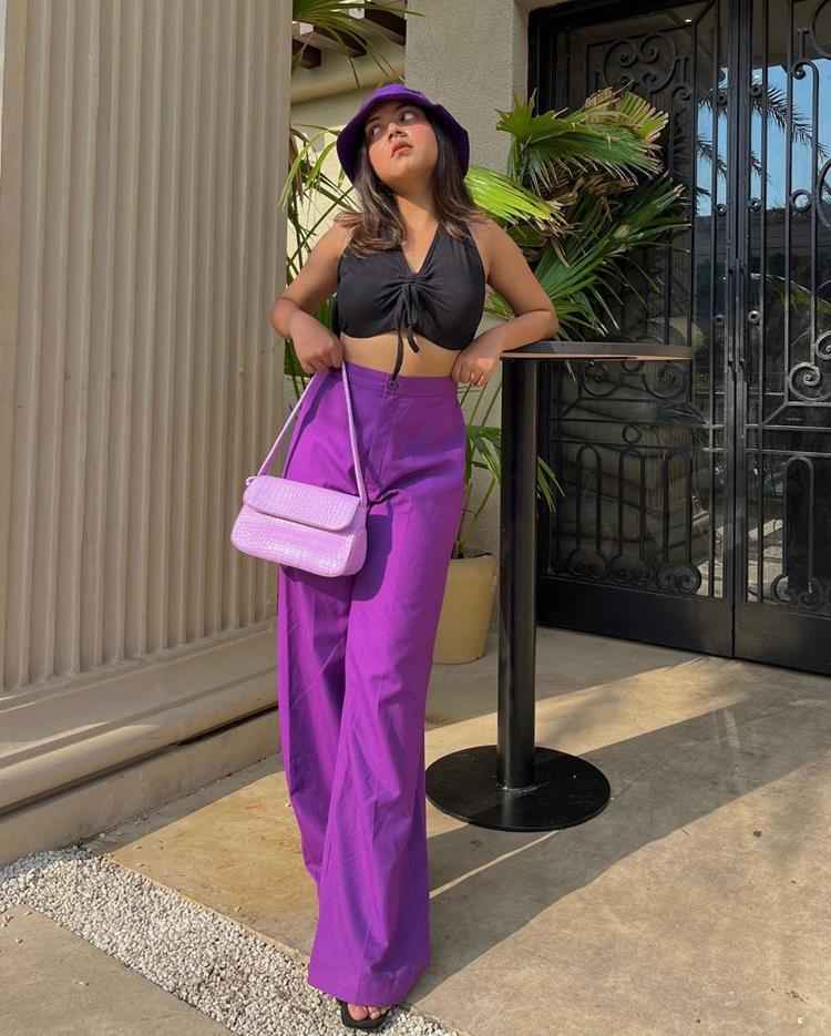 mulher com calça roxa e top preto