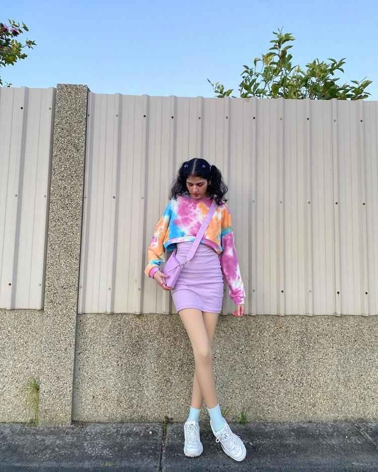mulher com saia lilás e moletom colorido