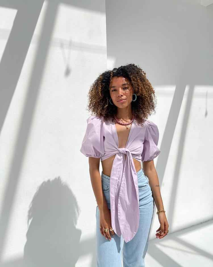 mulher com calça jeans e blusa lilás