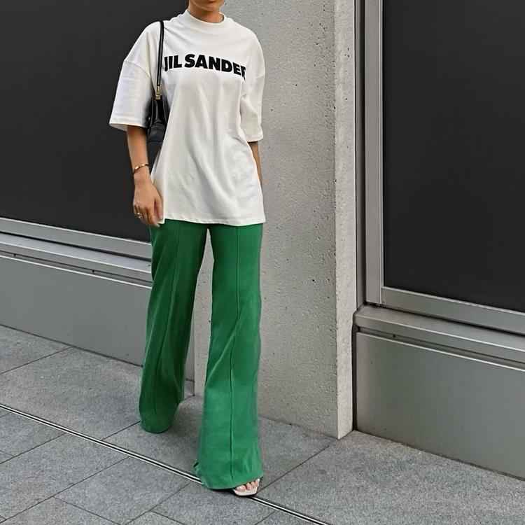 mulher com calça verde e camiseta branca