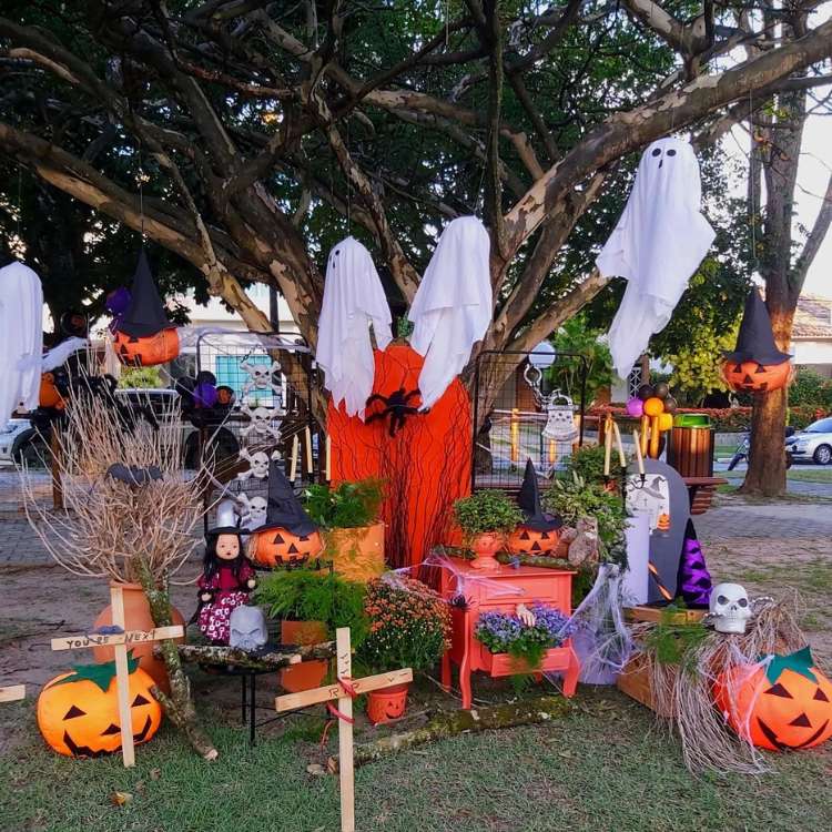Quintal decorado para o Halloween, com fantasmas pendurados, abóboras, bruxas e mais
