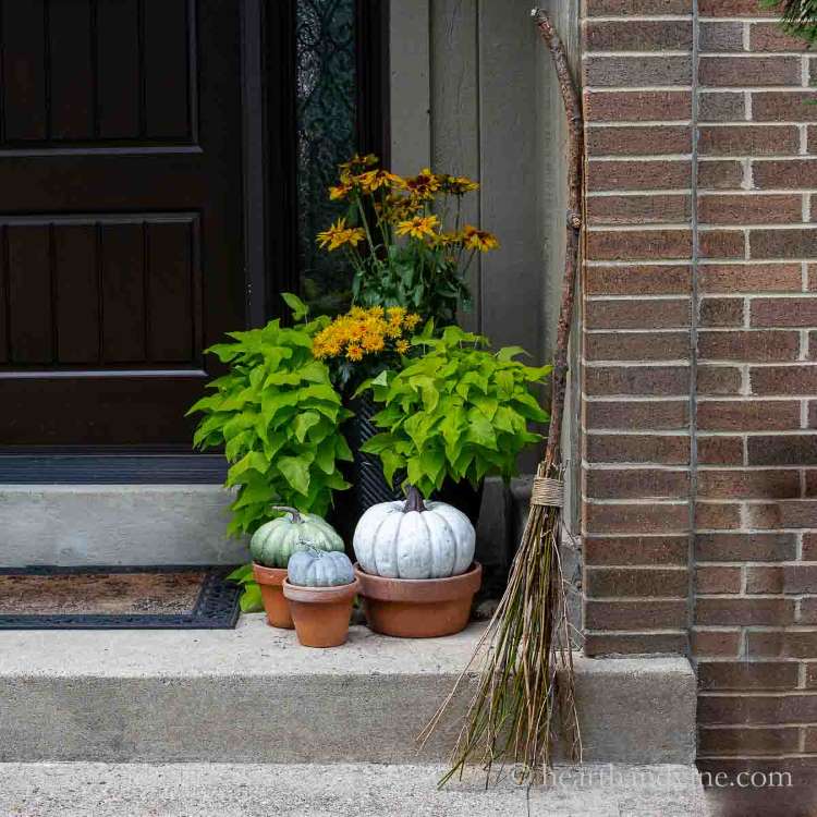 Abóboras em vasos e vassoura de bruxa de galhos secos na decoração externa de casa para o Halloween