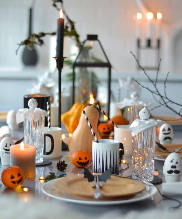 Mesa de café da manhã decorado no tema Halloween. Frutas, cabeças de alho e ovos com carinhas assustadoras