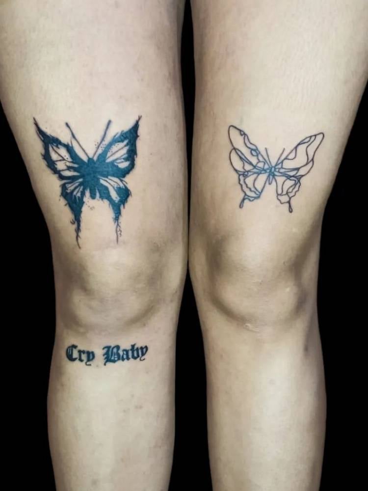Tatuagem de duas borboletas, uma acima de cada joelho de uma mulher de pele clara. Uma delas apresenta traços grossos, muito uso da tinta preta e a outra é mais delicada, com traços mais finos e sem sombreamento, 