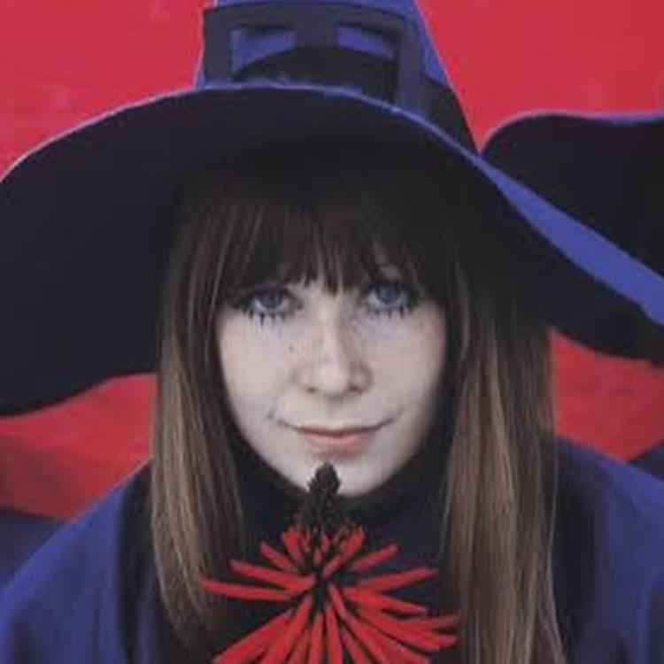 foto de rita lee jovem em fundo vermelho e chapéu de bruxa roxo