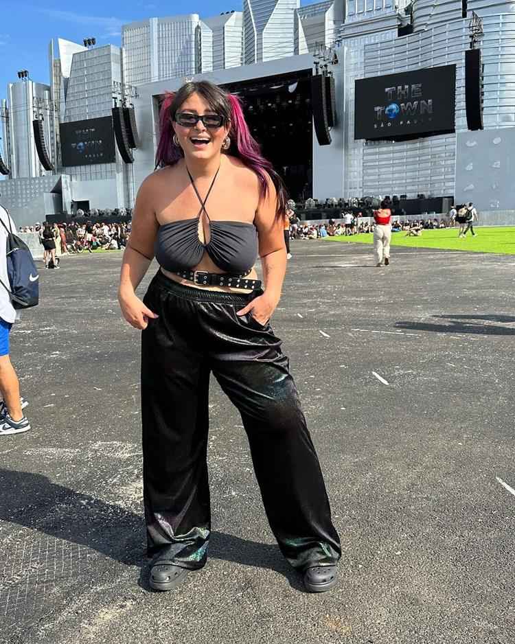 mulher no festival the town com top preto, cinto preto e calça e bota de mesma cor