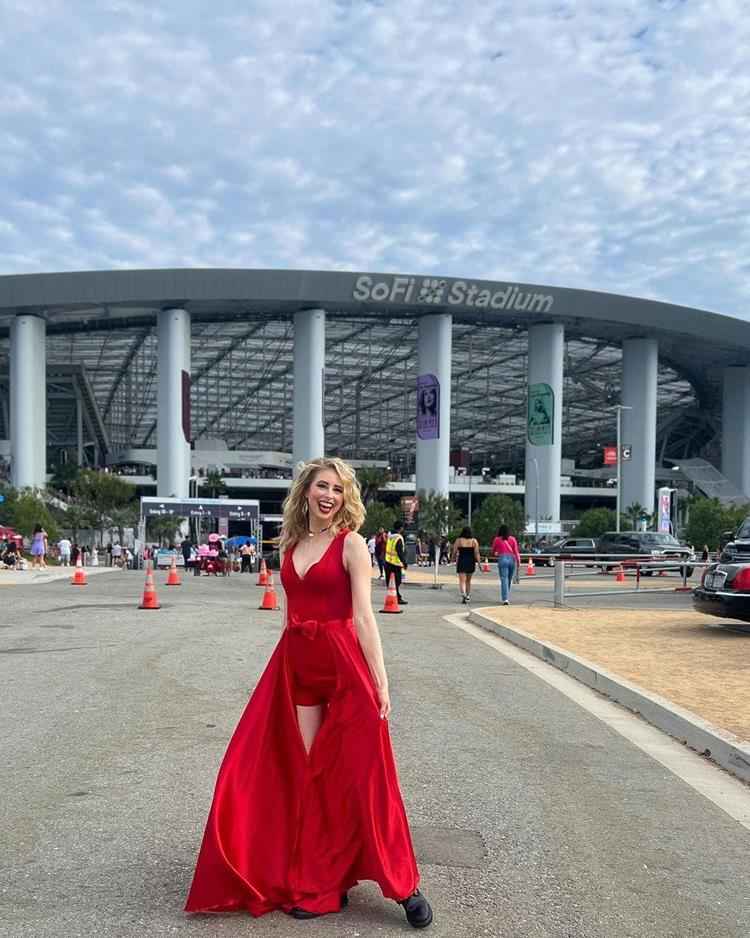 mulher na frente de estádio com vestido longo vermelho