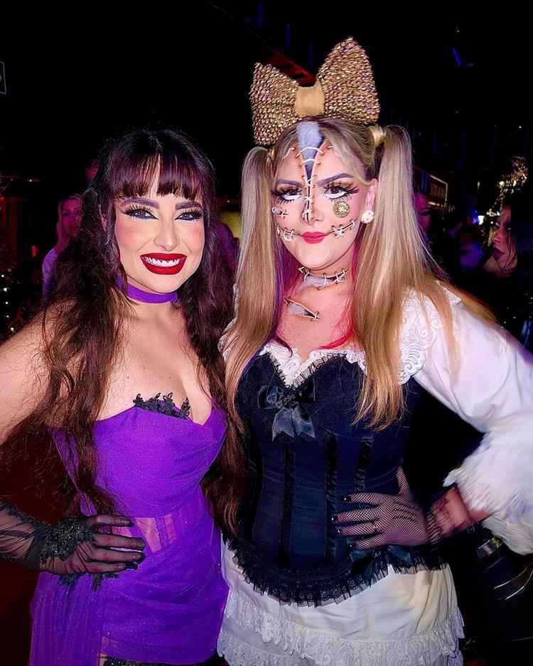 duas mulheres com fantasia de bruxa e boneca de pano