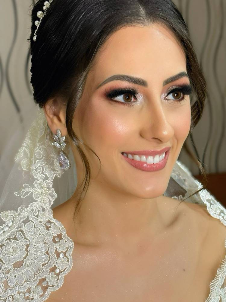 Noiva com maquiagem iluminada usando véu rendado e joias