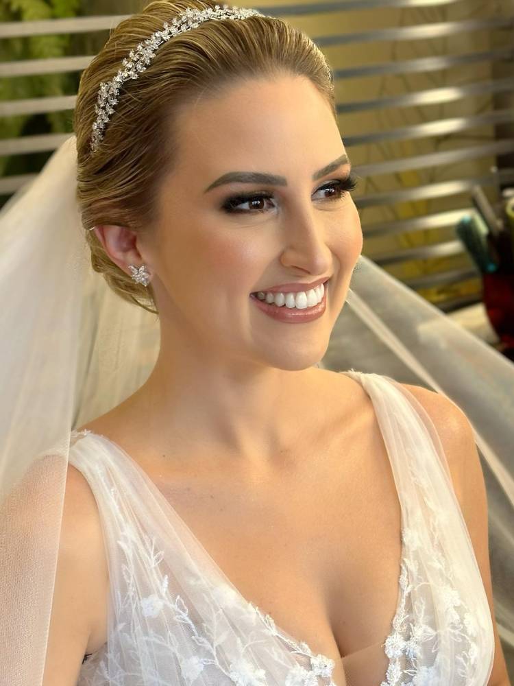 Maquiagem de noiva para casamento de manhã, ela está sorridente, usando joias brilhantes, véu e vestido de tule com renda