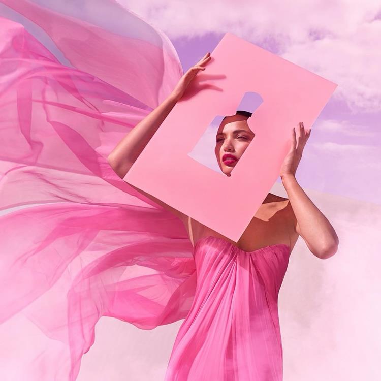 mulher em fundo lilás com vestido rosa leve no vento