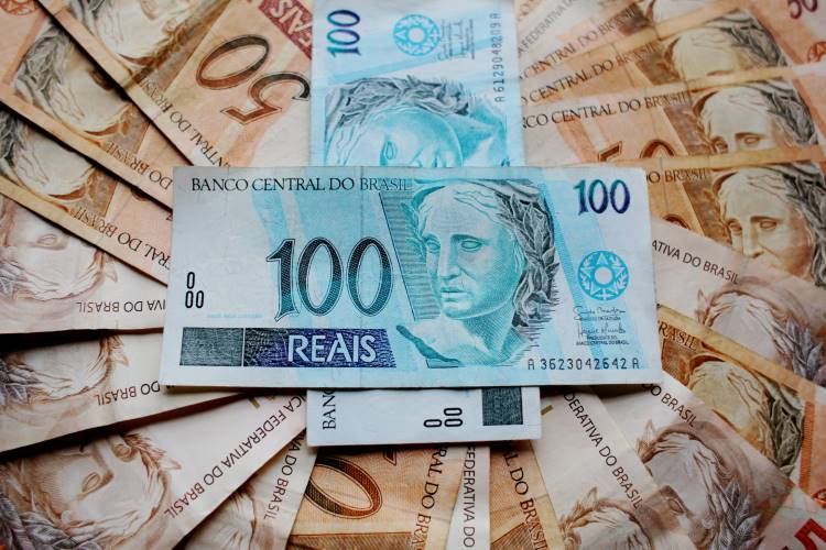 Notas de 50 reais espalhadas com duas notas de 100 reais em cima. 