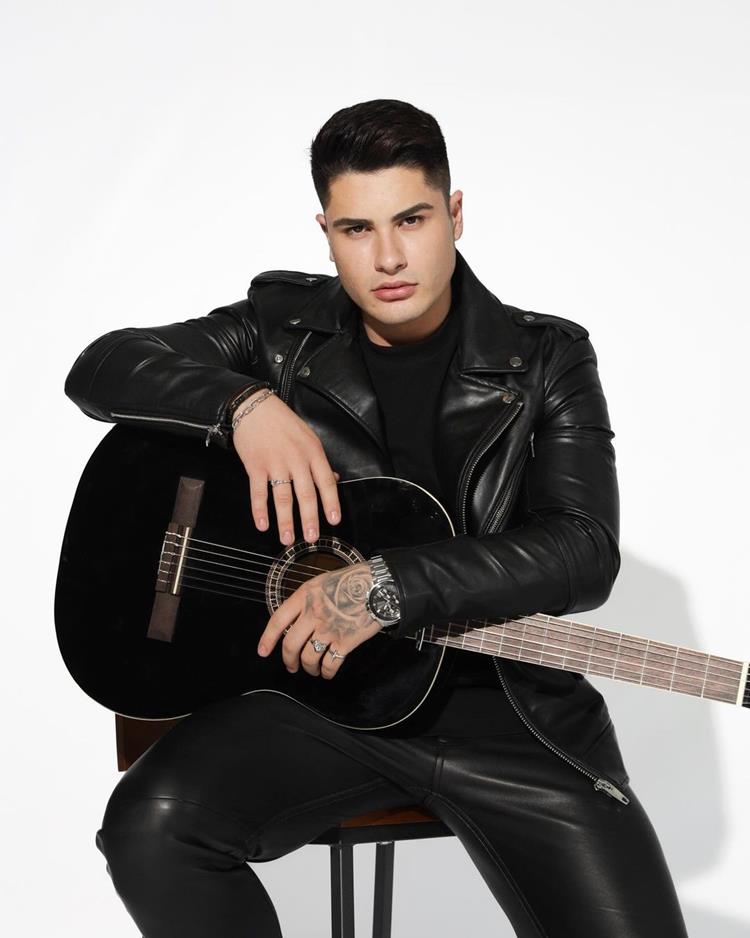 Lucas Souza com roupa preta segurando violão