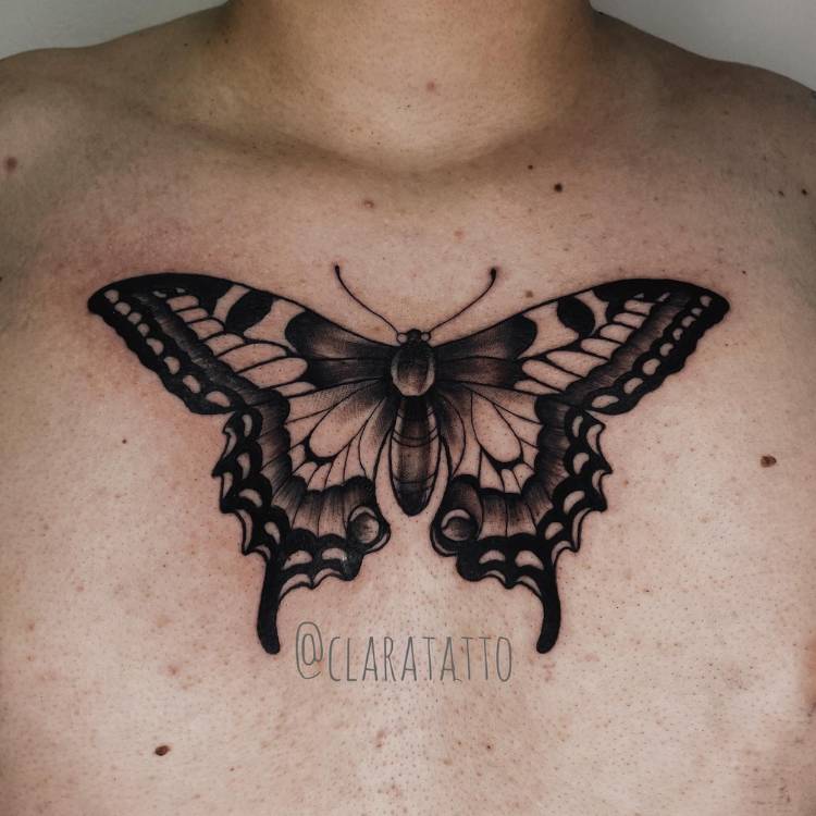 Tatuagem de borboleta com sombreamento na asa, traços grossos e feita no peitoral de um homem de pele clara.