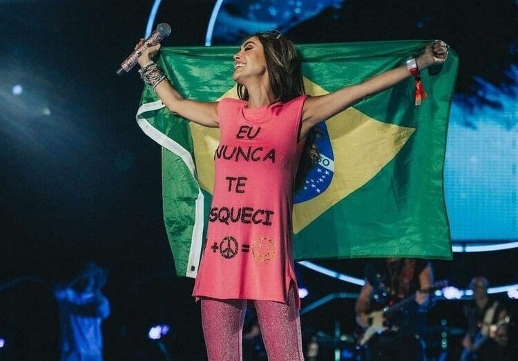 Anahí no show do RBD em São Paulo com um blusa rosa escrito em português "eu nunca te esqueci" e segurando uma bandeira do Brasil