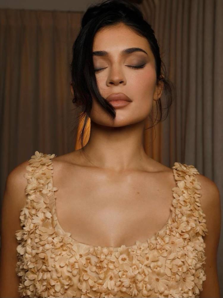 Kylie Jenner usando vestido dourado, maquiagem em tons terrosos e suaves, além de um matom barrom.