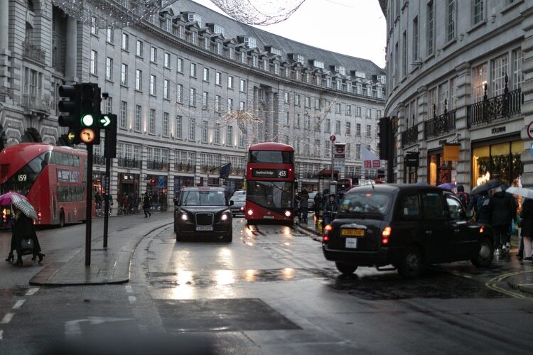 Dia de chuva em Londres com típicos taxis e ônibus londrinos passando pela rua