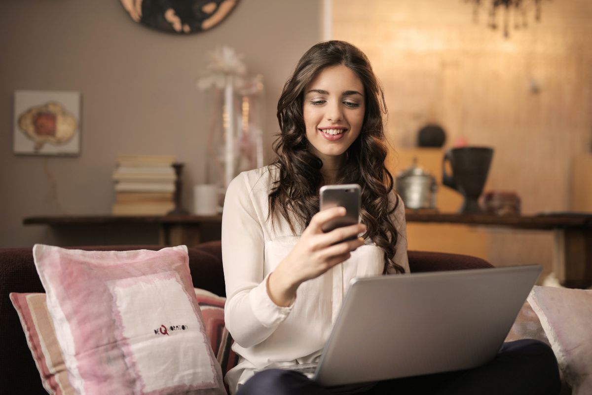 Mulher na frente de notebook com celular na mão explorando o mundo do cassino online