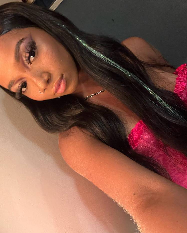 Selfie de SLipmami, usando tomara que caia rosa, corrente prata e maquiagem com delineado esfumado e cílios grandes. No cabelo um acessório de fios verdes brilhosos