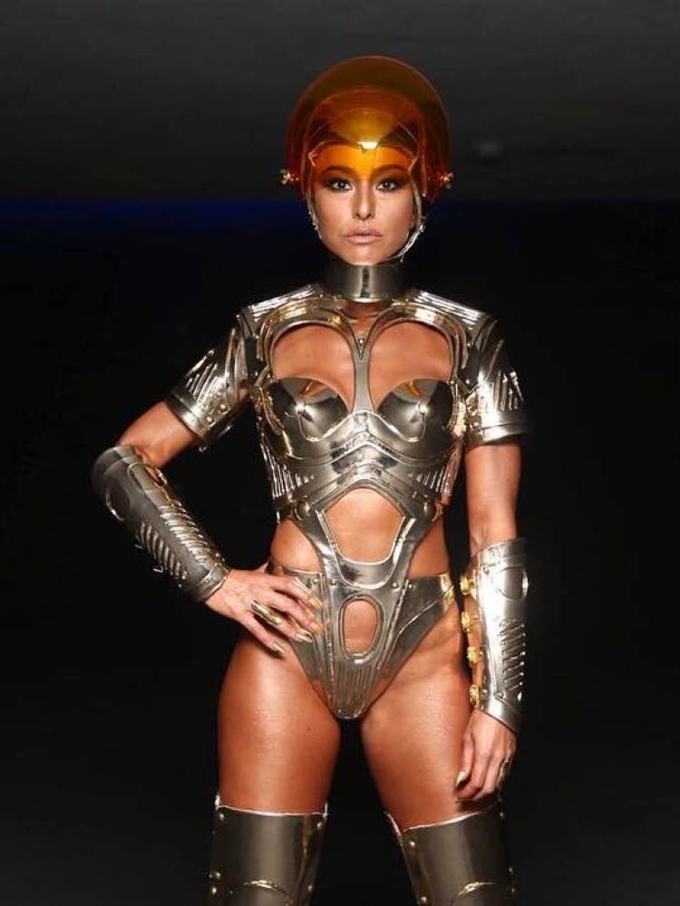 Sabrina Sato de body prata com recortes e capacete transparente laranja. 