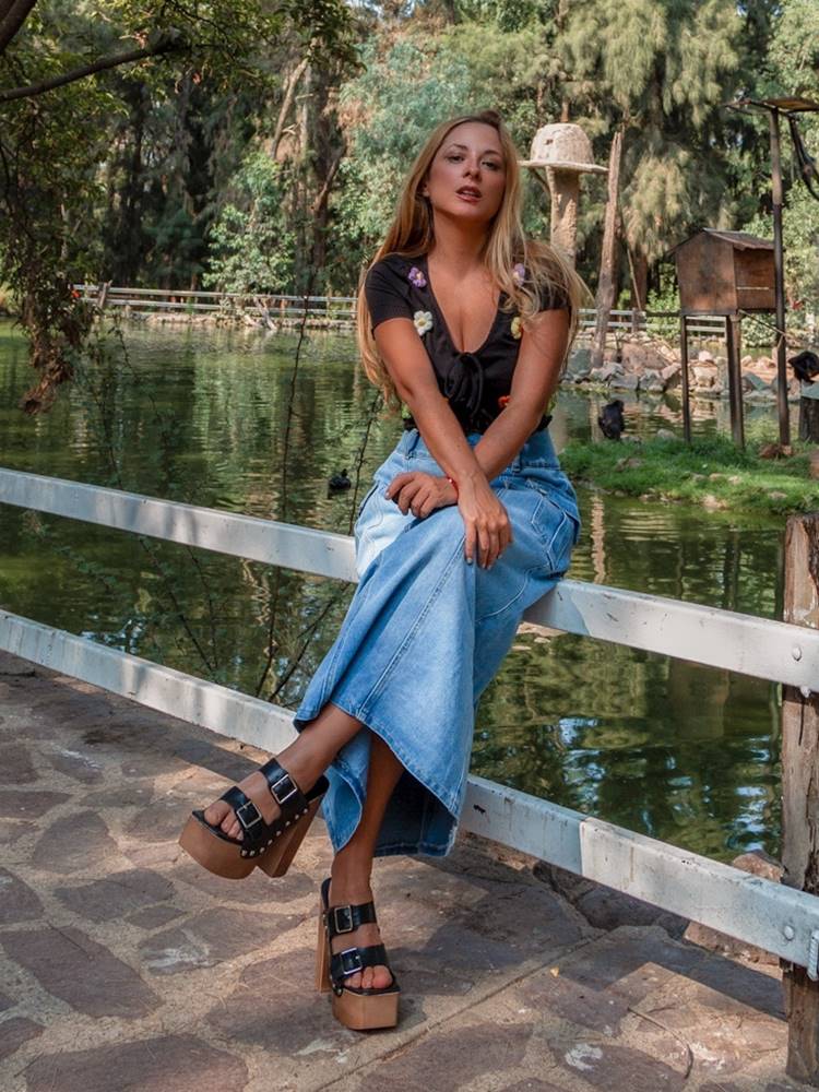 Mulher com look feminino a jovial sentada em cerca de parque com lagoa