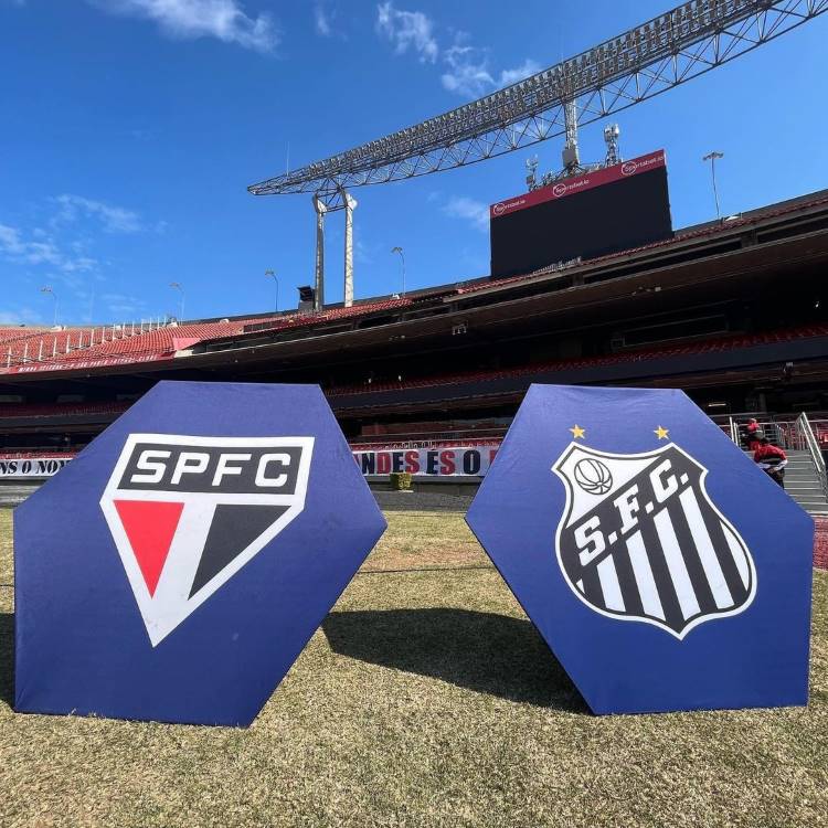 Duas placas hexagonais de fundo azul, uma com o escudo do São Paulo e a outra com o do Santos. As placas estão no gramado do Morumbi.
