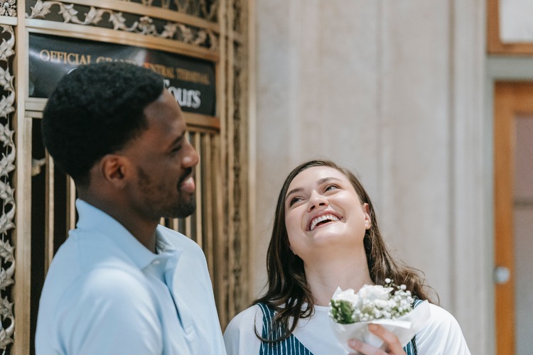 Homem negro dando flores para uma mulher branca que sorri para ele