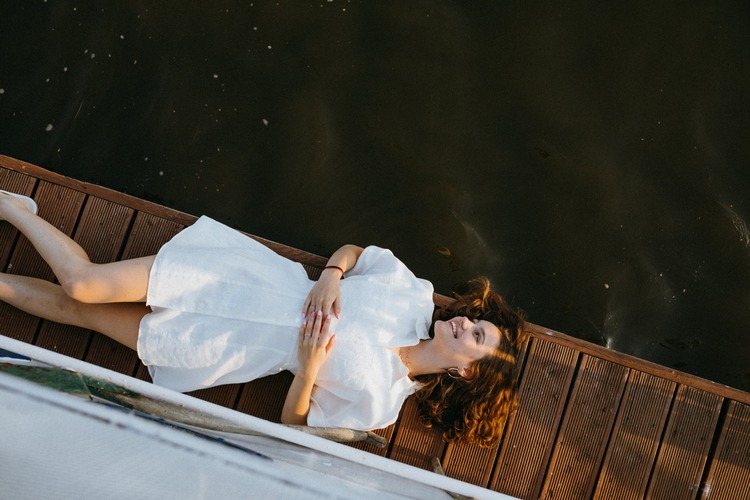 Mulher deitada em um deck perto de um rio sorrindo