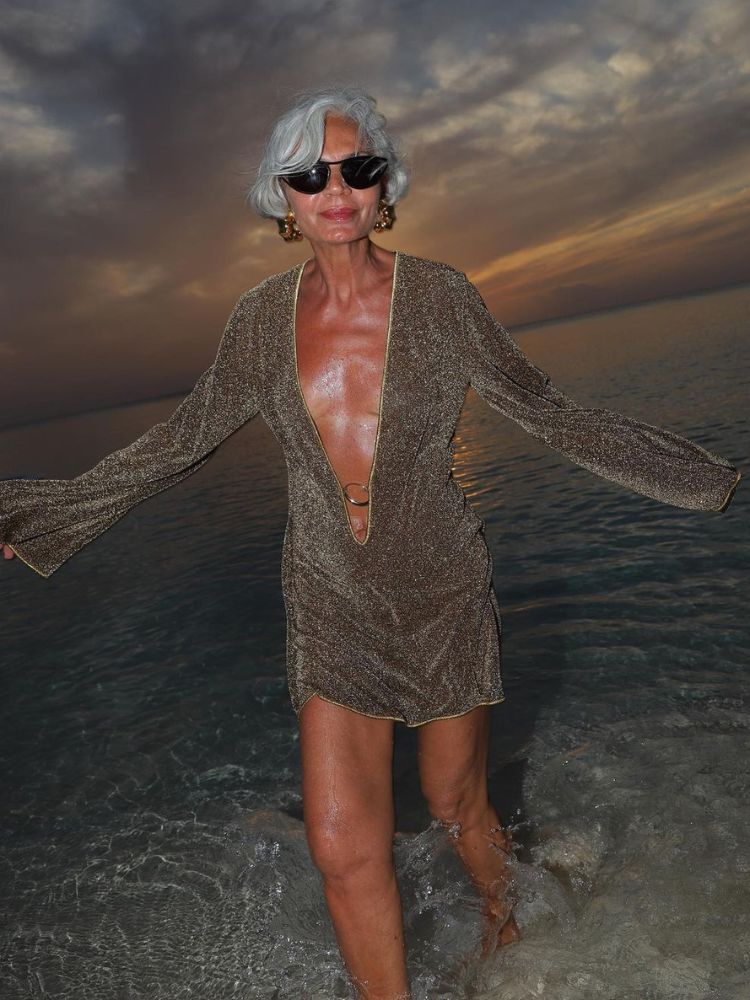 Grece Ghanem na praia usando roupa de ano novo dourada, um vestido curto com mangas longas de lurex
