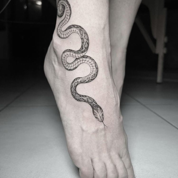 uma tatuagem de cobra que vai do fim da canela até o meio do pé