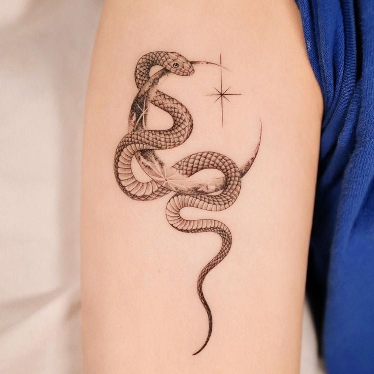 Uma tatuagem de cobra envolta em uma meia lua proxima ao ombro