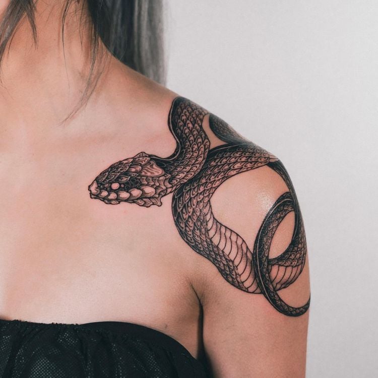 uma tatuagem pesada de cobra enrolada no ombro